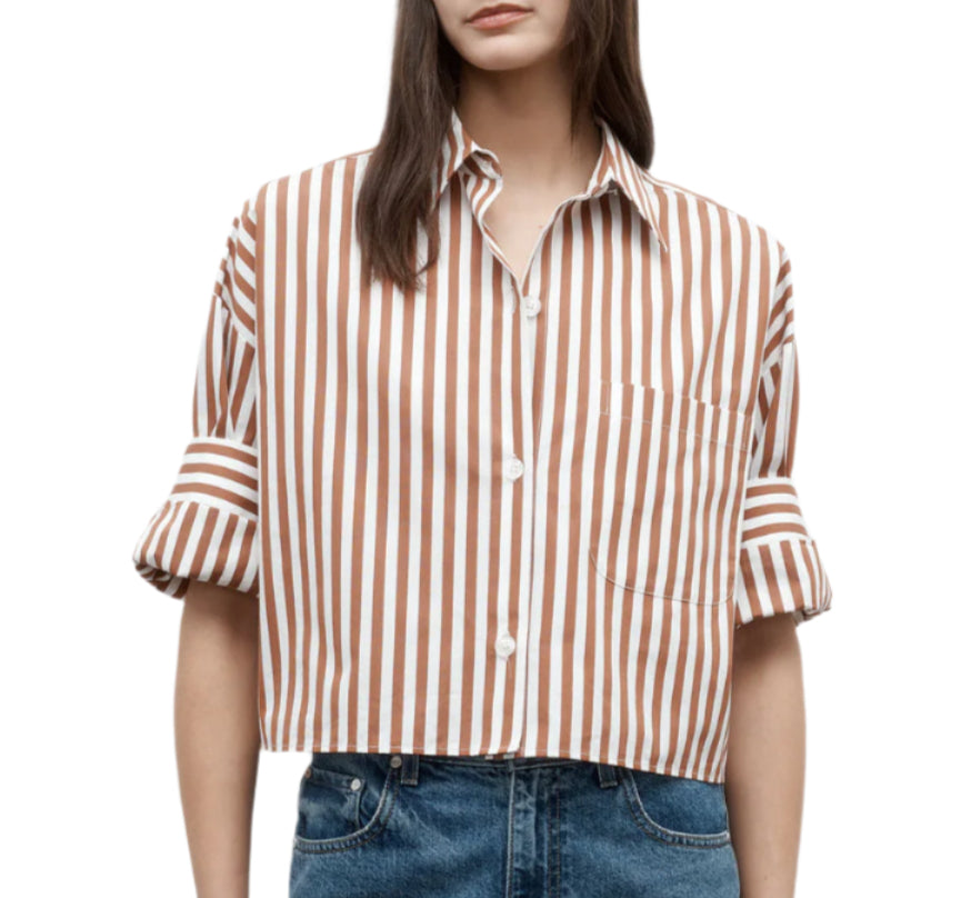 A woman wears the TWP Next Ex Stripe Shirt—a brown and white Italian cotton top with rolled sleeves and a boxy silhouette—paired with blue jeans.