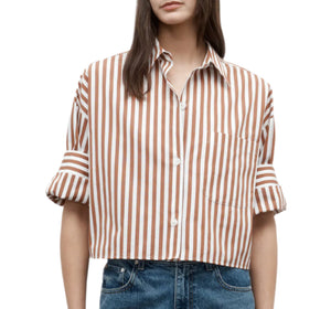 A woman wears the TWP Next Ex Stripe Shirt—a brown and white Italian cotton top with rolled sleeves and a boxy silhouette—paired with blue jeans.