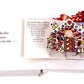 The pop-up book "12 Bugs of Christmas" by Simon & Schuster transforms into a delightful extravaganza featuring a vibrant gingerbread box illustration, with an excerpt from "The Twelve Days of Christmas" on the left page.
