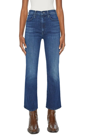 Shown from the waist down against a plain background, a person wears Mother’s The Hustler Ankle jeans with a white top and brown leather boots.