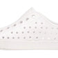 Native Shoes Kids’ Jefferson Shoes are white slip-on sneakers featuring round perforations, a white sole, and a small blue label on the heel. Shown in profile against a white background, these lightweight shoes are designed for comfort and everyday play.