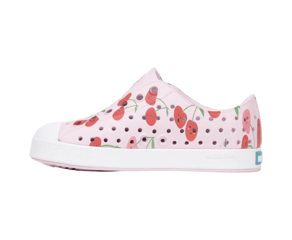 The Kids’ Jefferson Print Shoes by Native Shoes feature a cheerful cherry pattern and ventilation holes, with the signature white rubber toe cap and a shock-absorbent sole for comfort.
