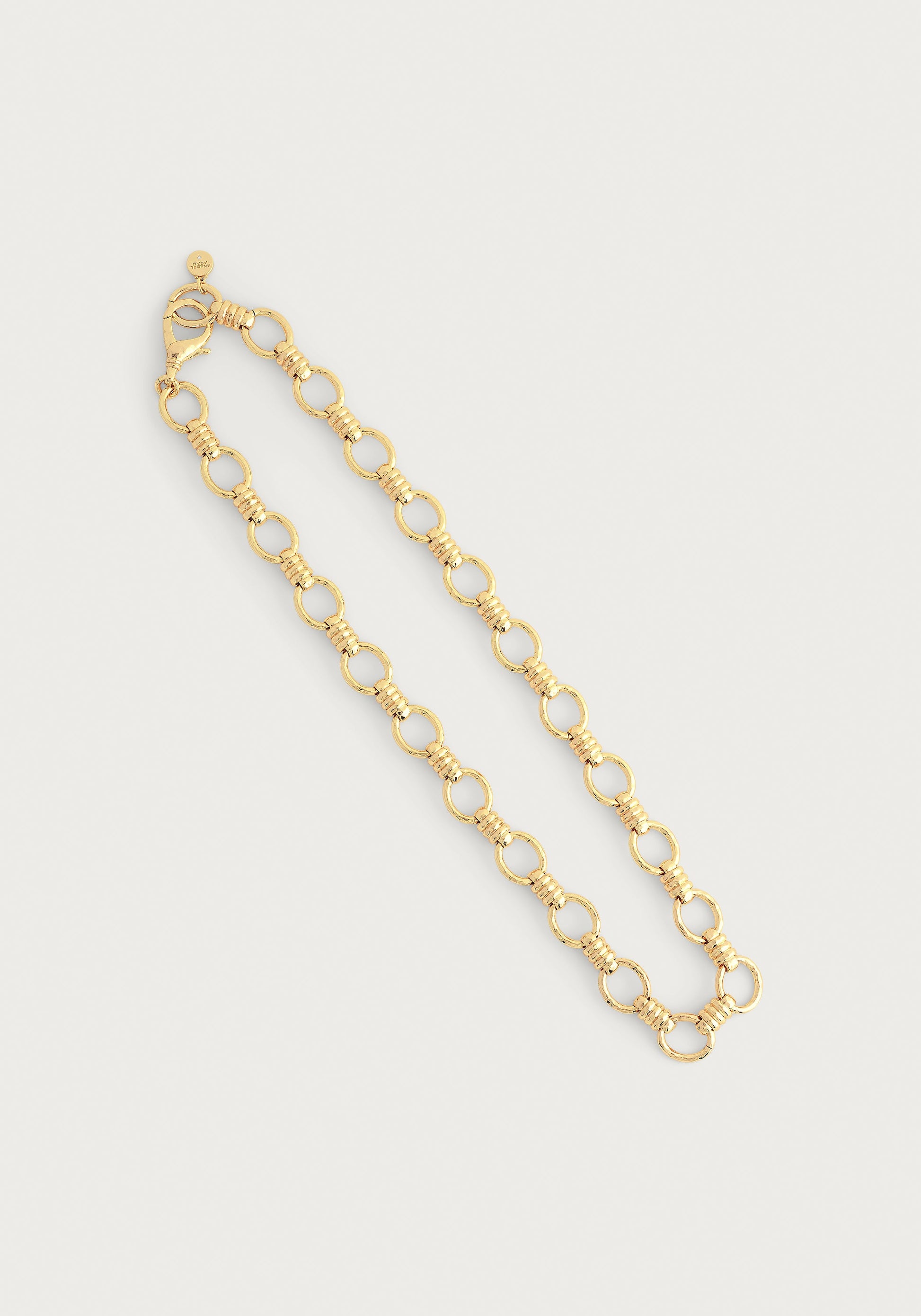 The Anabel Aram Neptune Chain Necklace features circular links with textured detailing, dipped in 18k gold for a radiant finish—an elegant piece shown on a plain white background.