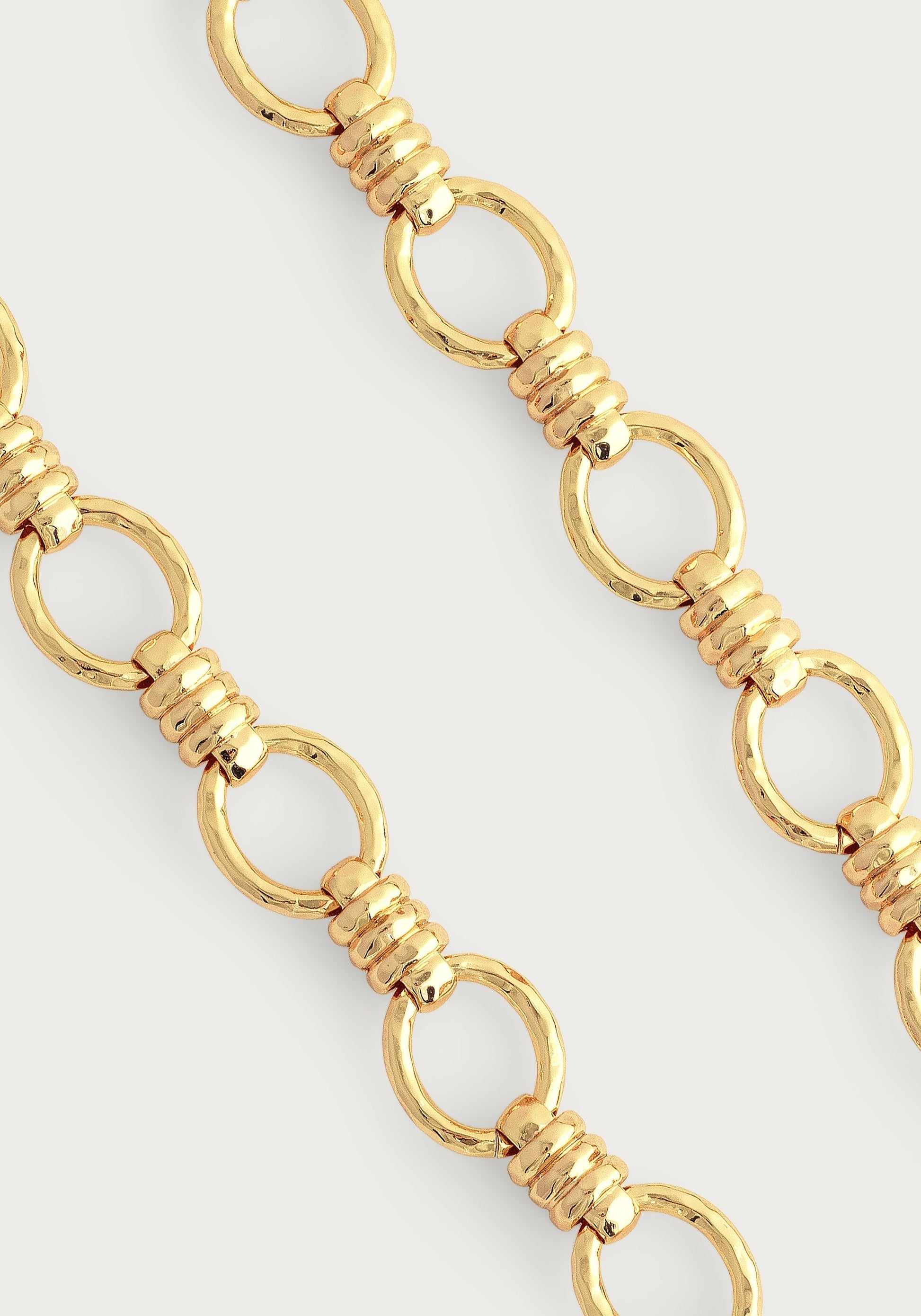 Close-up of Anabel Aram’s Neptune Chain Necklace, showcasing round links joined by trios of small 18k gold dipped rings, set against a simple light background.
