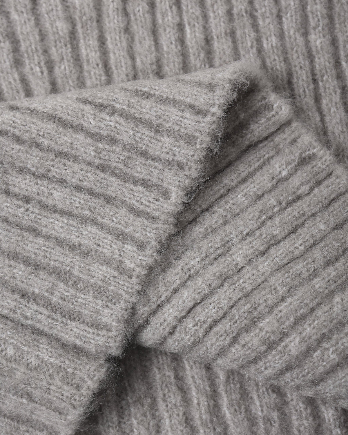 Close-up of a folded gray knitted fabric with a ribbed texture, reminiscent of the cozy Girls’ Fuzzy Knit Lounge by Rylee & Cru, featuring soft, wide leg pants.