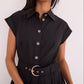 A woman wears the Octavia Dress by Cara Cara—a black belted shirtdress with short sleeves, decorative buttons, and a matching black belt with metallic buckle.