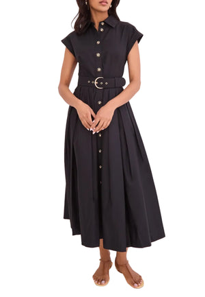 A woman stands against a plain white background wearing the Cara Cara Octavia Dress, a sleeveless, belted shirtdress with a button-down front and box pleat skirt, paired with sandals.