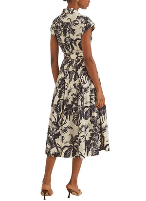 A woman shown from the back wears the Octavia Dress by Cara Cara, featuring a crisp belted design with short sleeves, a collared neckline, and a black-and-white floral midi skirt, paired with beige heeled sandals for a polished look.