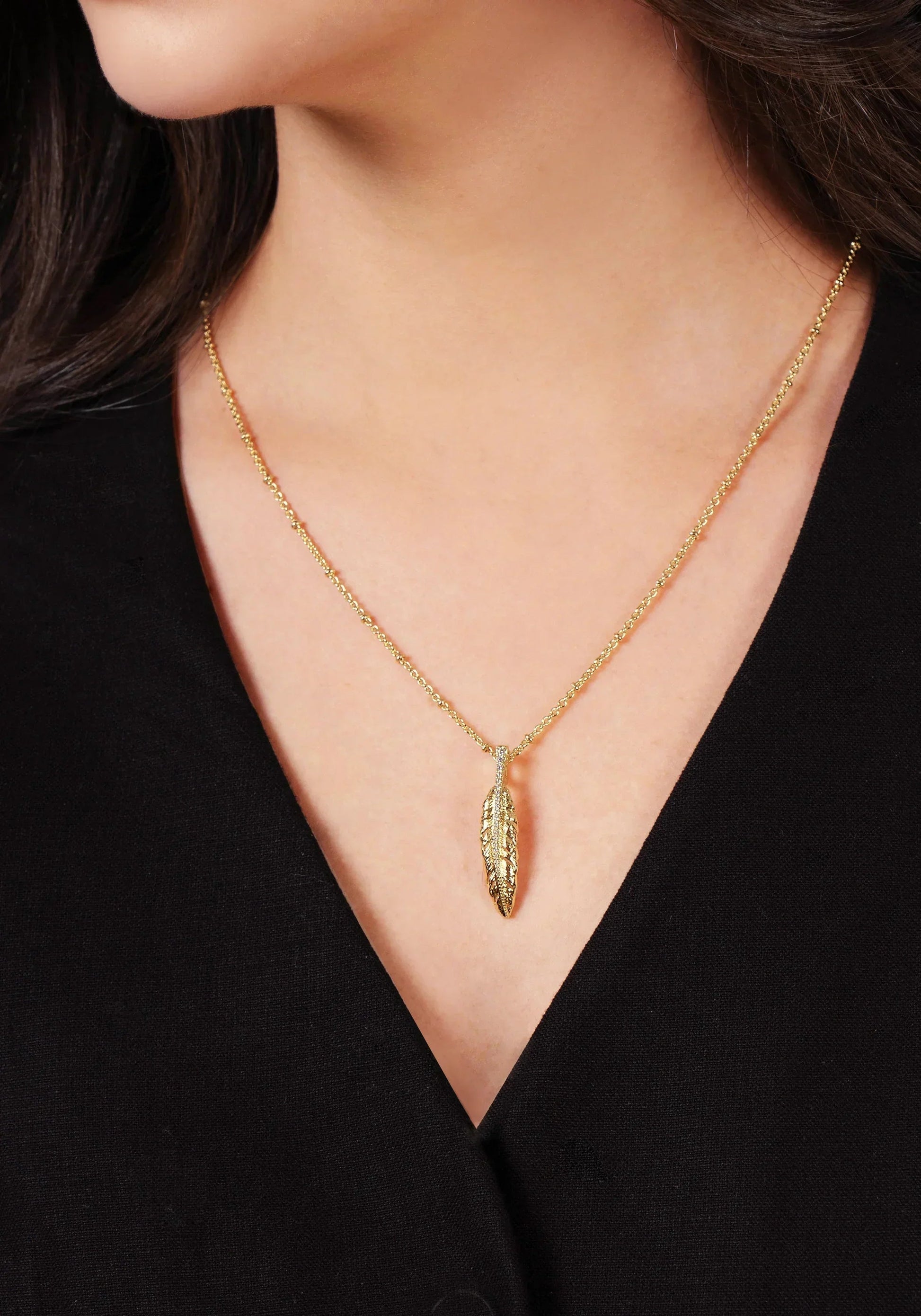 A person wearing the Anabel Aram Molten Bead Chain Necklace in gold, styled over a plain black top.