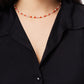 A woman wearing a black textured button-up shirt and the Milos Beaded Necklace by Anabel Aram, featuring red, white, and turquoise beads.