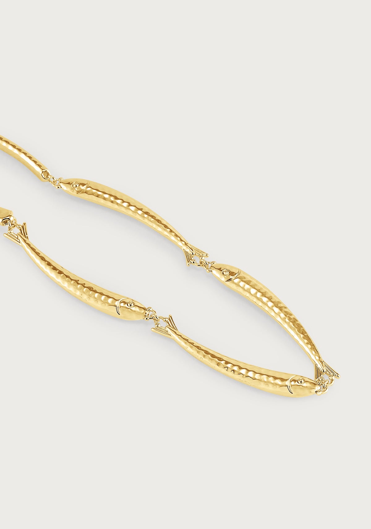 Anabel Aram Milos Fish Necklace featuring an 18K gold plated chain of connected fish charms with textured, metallic scales.