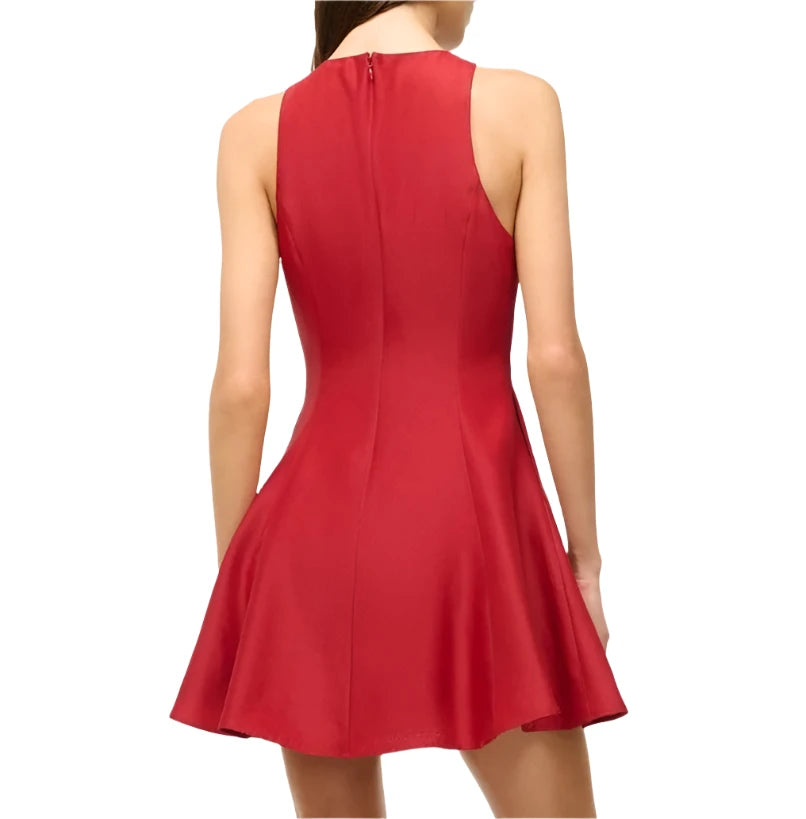 A woman is shown from the back wearing the Staud Mini Heike Dress, a sleeveless piece in red silk wool, featuring a fitted waist and full skirt.