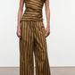 A person wearing the Staud Mateo Cotton Poplin Pant, a wide-leg, mid-rise style with a drawstring waist in a brown and yellow vertical stripe pattern, paired with a matching off-shoulder cotton poplin top, stands on a smooth indoor floor against a plain background.