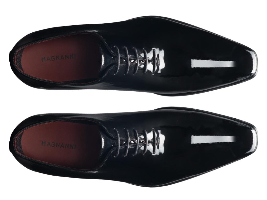 Top-down view of a pair of shiny black patent leather Magnanni Cruz II Tux Shoes with laces, aligned horizontally, epitomizing the elegance of the Magnanni Core Collection.