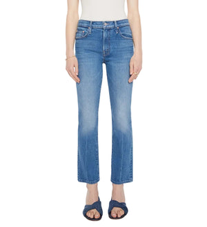 A person wearing Mother’s The Insider Ankle high-rise bootcut jeans, a white sleeveless top, and dark blue sandals stands against a plain background.