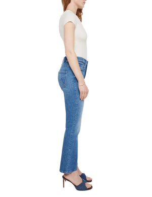 Woman in profile wears The Insider Ankle jeans by Mother, crafted from SUPERIOR denim, paired with a short-sleeve white top and blue heeled sandals. Made in Los Angeles. Set against a white background.