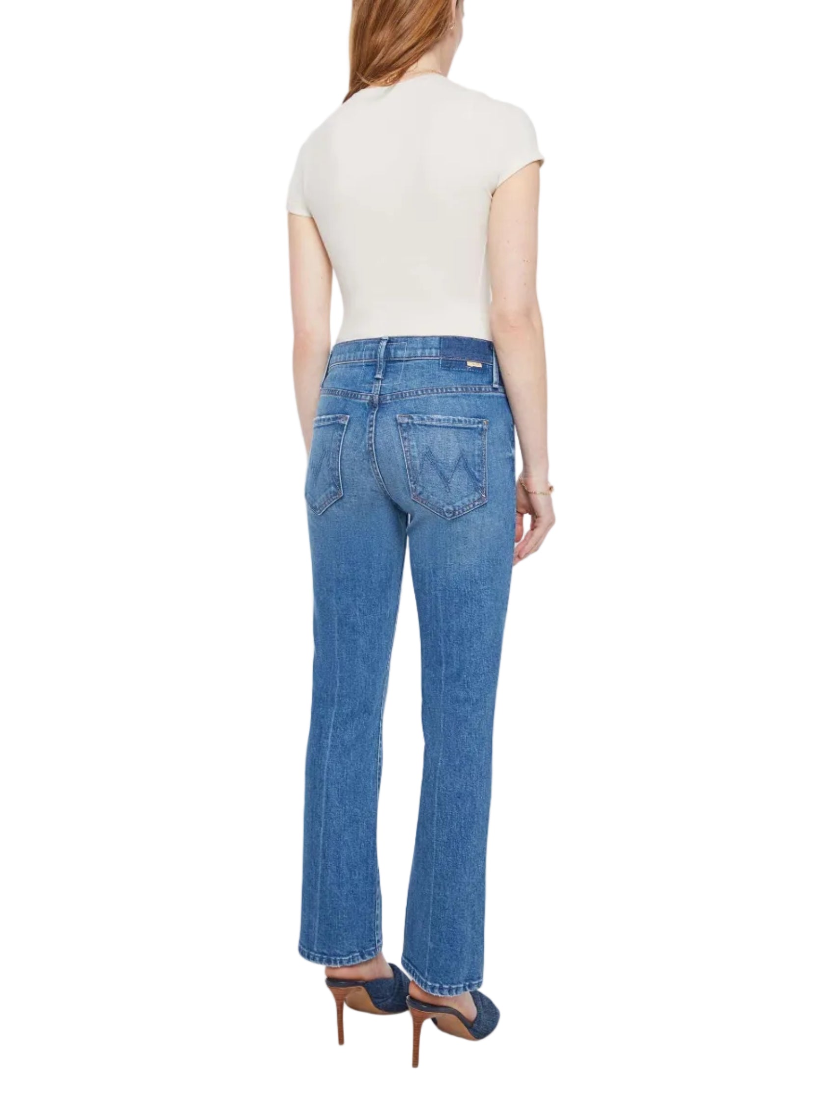 A person wearing a short-sleeve white top, The Insider Ankle high-rise bootcut jeans by Mother crafted from SUPERIOR denim, and high-heeled shoes stands facing away from the camera against a white background. Made in Los Angeles.