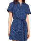 A woman wears the Cara Cara Asbury Dots Mini Dress, featuring short sleeves, blue fabric with white polka dots, a button-down front, and a self-tie waist.