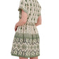 A woman stands with her back to the camera against a white background, wearing the Cara Cara Asbury Mini Dress— a short-sleeve cream and green placed print shirtdress.