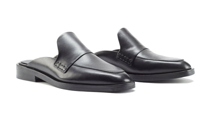 A pair of black 3.1 Phillip Lim Alexa Loafer Mules crafted from smooth calf leather, featuring a sleek design and backless slip-on style with a flat heel.