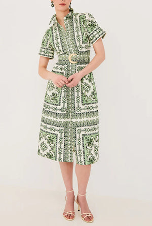 A person wears the Cara Cara Malena Dress—a green and white patterned, belted short-sleeve dress—with beige heeled sandals, standing against a plain light background.