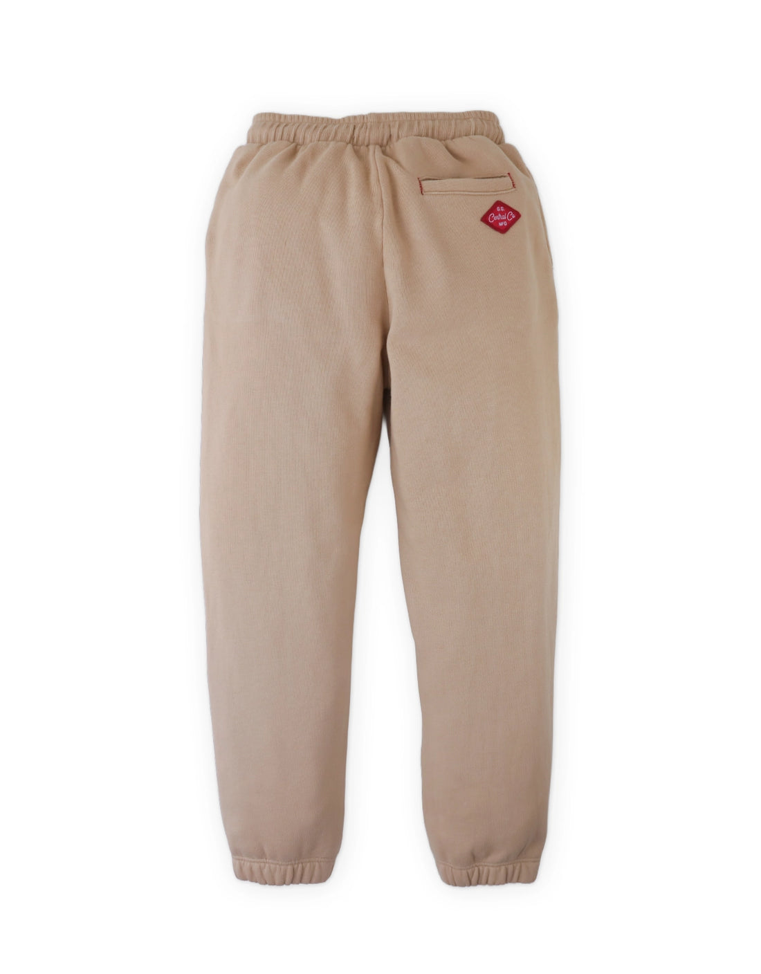 The Boys’ Giulio Jogger Pants by Gingersnaps feature a beige fleece design with an elastic waistband and cuffs, a single back pocket on the right side, and a small red logo patch above the pocket, shown against a white background.