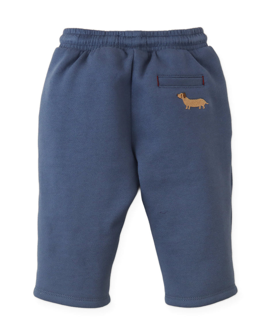 The Gingersnaps Baby Boys’ Sonny Pant features a navy blue fleece design with an elastic waistband, a small front pocket, and an embroidered yellow dog on the left side—an everyday essential for playful comfort.