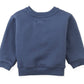 The Gingersnaps Baby Boys’ Riccardo Pullover is displayed flat with its front side visible, showcasing ribbed cuffs, waistband, and collar. This cozy navy blue fleece sweatshirt features a charming embroidered dachshund for a playful accent.