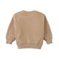 The Baby Boys’ Ennio Pullover by Gingersnaps is displayed from the back in beige, featuring ribbed cuffs and waistband. Crafted in a soft fleece pullover style, this long-sleeve crewneck essential is laid flat on a white background—perfect for effortless street-style looks.