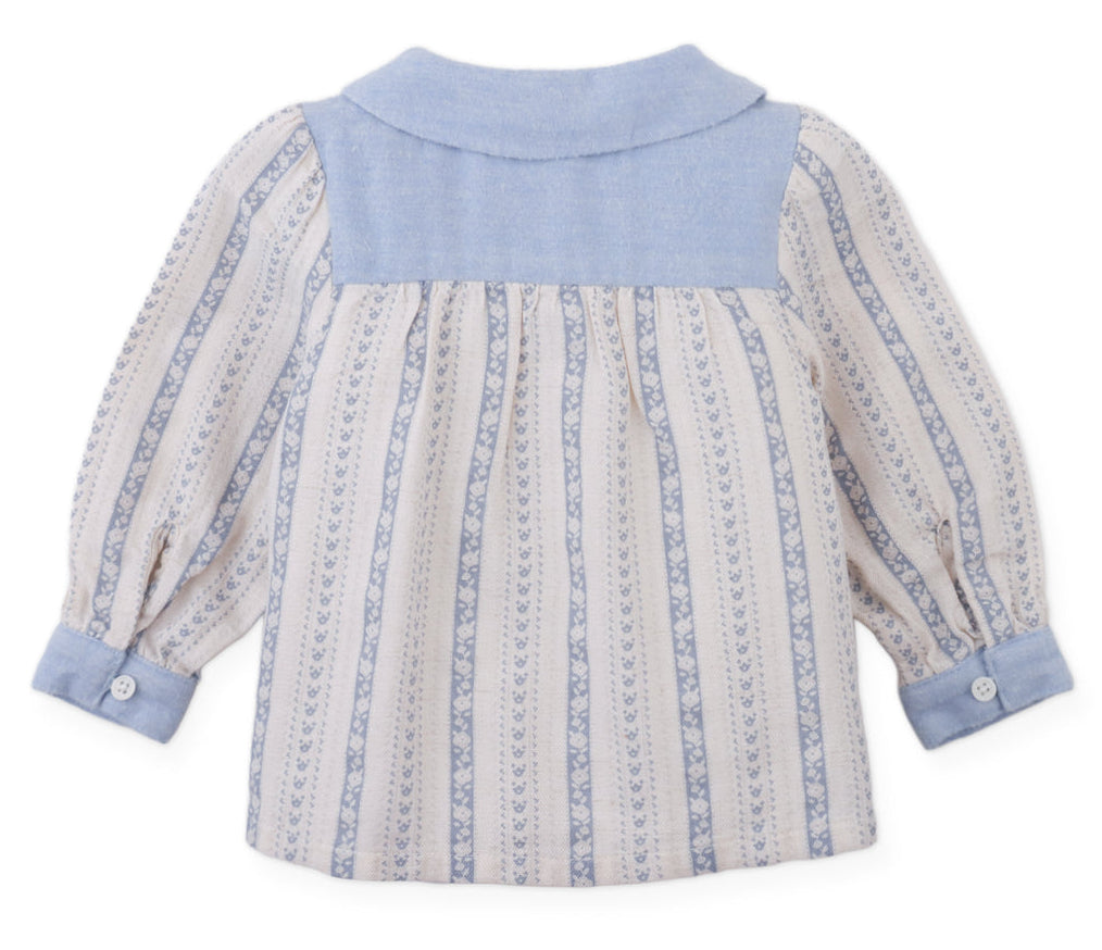 The Gingersnaps Baby Girls’ Hester Striped Floral Blouse features long sleeves, blue patterned stripes, a solid blue yoke and collar, and blue buttoned cuffs. Displayed flat with the back facing up, it’s the perfect cozy blouse for fall and winter.