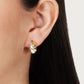 Close-up of a person's ear wearing Anabel Aram's Farrier Triple Huggie Hoop Earrings in gold and silver with a hammered texture; straight dark hair partially visible.