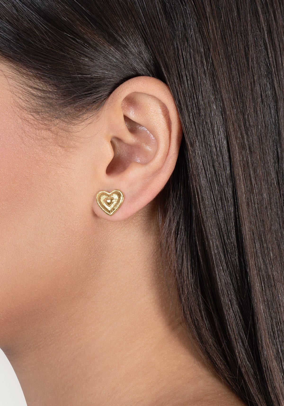 Gold Heart Radiant Stud earring worn on an earlobe.