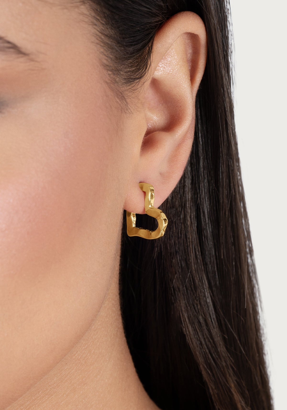 Small Heart Hoop Earrings in 18K gold-plated metal worn in an earlobe.