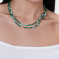 Anabel Aram Milos Beaded Necklace featuring green, turquoise, and lapis lazuli beads interspersed with small gold-toned cylindrical and spherical spacers.