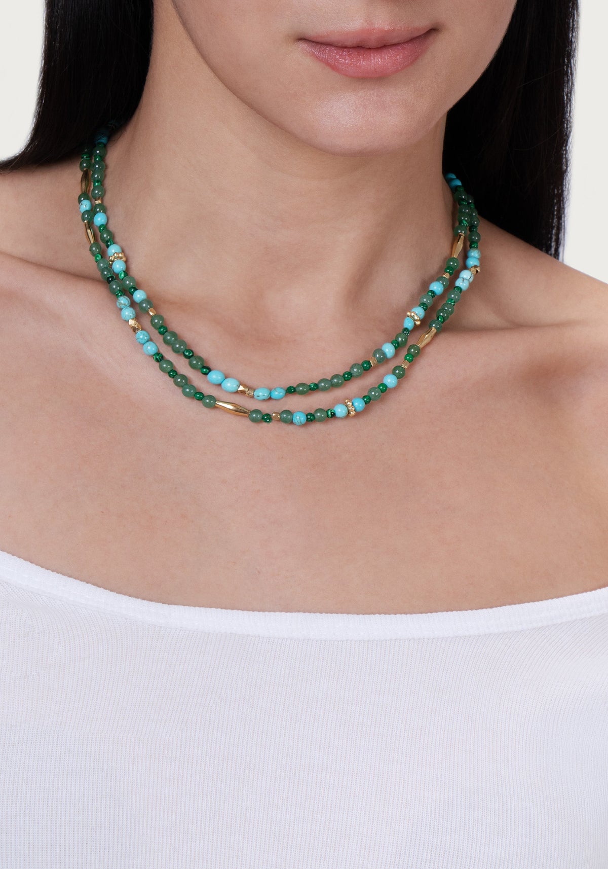 Anabel Aram Milos Beaded Necklace featuring green, turquoise, and lapis lazuli beads interspersed with small gold-toned cylindrical and spherical spacers.