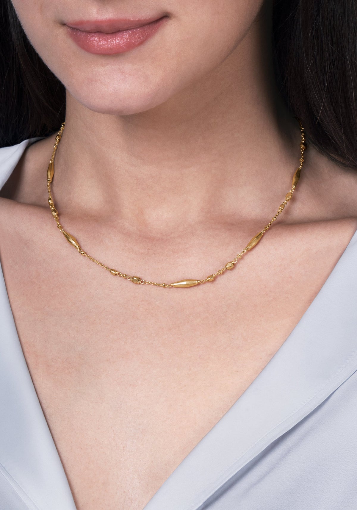 The Anabel Aram Milos Multi Beaded Necklace is a delicate 18k gold plated piece featuring small, smooth, elongated beads spaced along the strand.