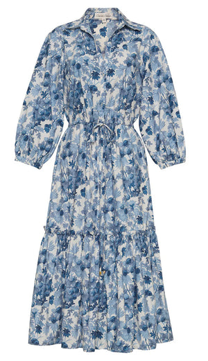 The Hutton Dress by Cara Cara is a versatile long floral dress in a blue and white pattern, featuring a collar, puff sleeves, and a tie waist.