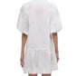 A woman is seen from the back wearing the Simkhai Crissy Dress, a mini dress with puffed sleeves and a ruffled hem in casual shirting fabric, set against a plain background.