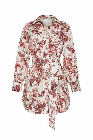 The Cara Cara Villena Dress is a long-sleeve, button-down shirt dress with a collar, chest pocket, and waist tie, featuring a red and white botanical and animal print.