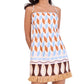 A woman wears the Cara Cara Valencia Mini Dress, a sleeveless shift mini with thin straps, geometric patterns in brown, blue, and tan, and raffia fringe at the hem.