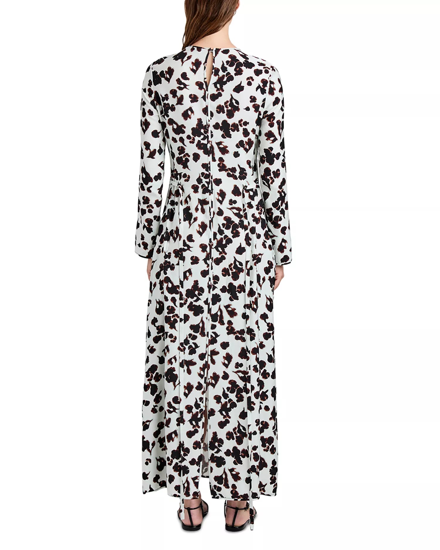 A woman seen from the back wears the Waverly Dress by Proenza Schouler White Label—an ankle-length, long-sleeved dress with a black and brown abstract floral print—paired with black sandals.