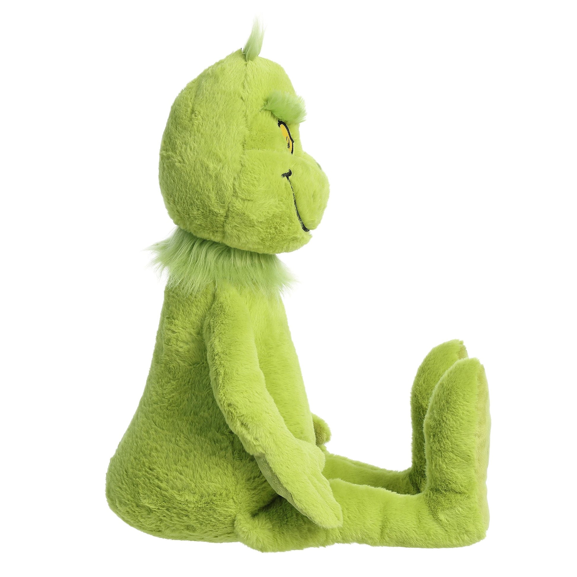 A side view of an Aurora Dr. Seuss Grinch, Jumbo plush toy is shown sitting upright with legs extended and arms at its sides, set against a white background.