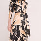 A person wears the Cara Cara Montgomery Silk Midi Dress in beige hammered silk with a bold black floral print and matching belt, standing against a plain light background.