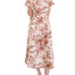 A woman wears the Cara Cara Sawyer Dress, a light-colored, short-sleeved collared shirtdress with a brown floral print, paired with beige sandals.
