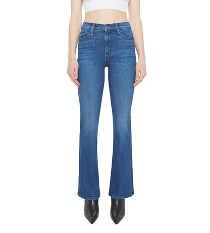 A person wears The Weekender by Mother—blue bootcut flare stretch denim jeans—with black pointed shoes and a white cropped top; jeans are shown from the front.