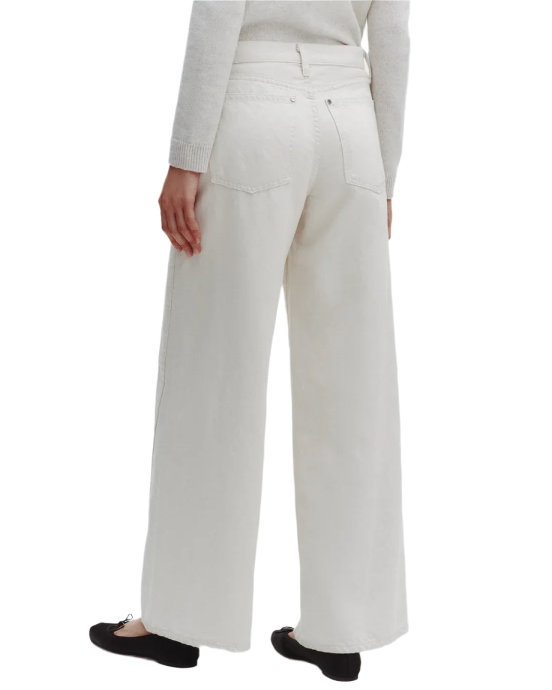 Shown from the back, a person wears TWP’s Almost Famous Pant—relaxed fit, wide leg, off-white cotton linen denim with two back pockets—paired with a light sweater and black flats for an effortlessly chic look.