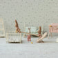 Three Maileg "Rabbit with Dots - My" plush baby dolls stand in a miniature nursery featuring a crib, cradle, high chair, changing table, and other charming baby furniture arranged on a light patterned background—perfect for adding character to any dollhouse or inspiring creative babysitter play.