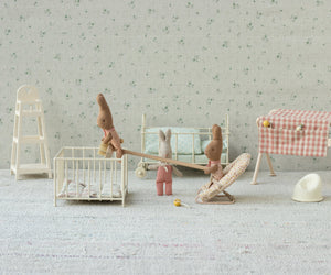 Three Maileg "Rabbit with Dots - My" plush baby dolls stand in a miniature nursery featuring a crib, cradle, high chair, changing table, and other charming baby furniture arranged on a light patterned background—perfect for adding character to any dollhouse or inspiring creative babysitter play.