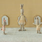 Three Maileg Rabbit Size 1, Classic - Ballet Suit and Skirt Cream dolls stand in front of small mirrors against a patterned wall and light-colored floor, dressed in ballet costumes with delicate tulle skirts, ready to dance gracefully.