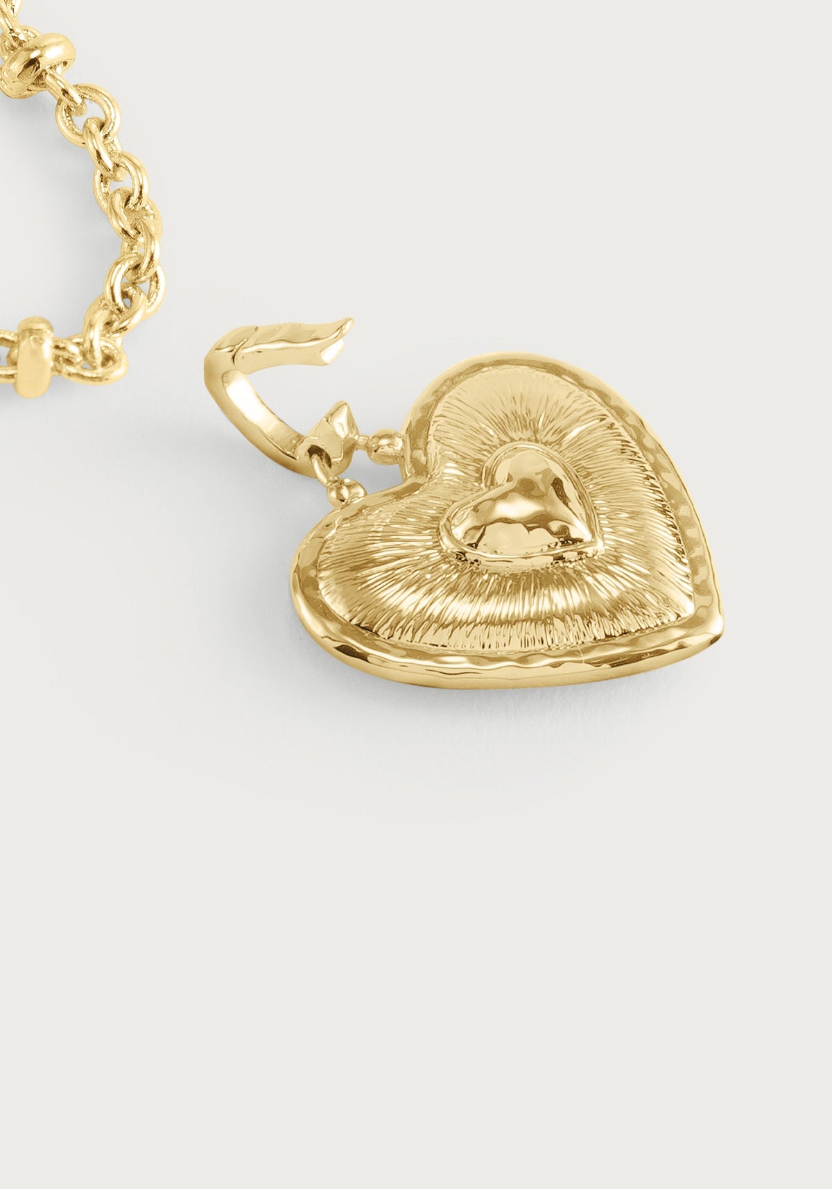 Gold-toned Anabel Aram Heart Radiant Charm with a textured border and smooth center, attached to a metal chain link.